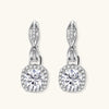 Sterling silver twisted hoop earrings with round moissanite stones in halo settings against neutral background.