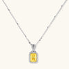 Platinum-plated 925 sterling silver necklace with a yellow radiant-cut moissanite pendant in a sparkling halo on a cream background.