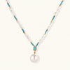 Beaded necklace with baroque pearls, turquoise stones, and gold accents featuring a large pearl pendant on white background.