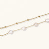 Double-strand gold bracelet with irregular baroque pearls and smooth freshwater pearls on cream background.
