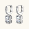 Sterling silver huggie hoops with emerald-cut moissanite drops featuring pavé-set crystals on white background.