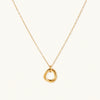 Delicate gold-plated necklace with three interlocking circle rings forming a minimalist knot pendant on cream background