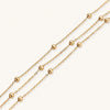 Three-strand gold-plated bracelet with clustered ball beads and adjustable clasp on cream background