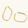Set of geometric gold-plated sterling silver hoop earrings in oval and cushion shapes on cream background